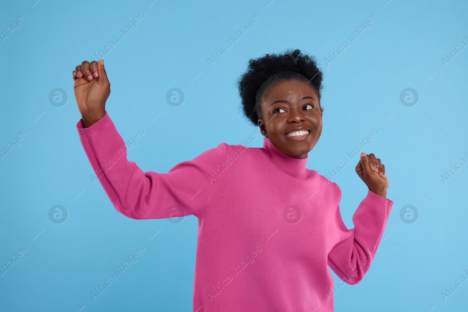 Photo of Happy young woman dancing on light blue background