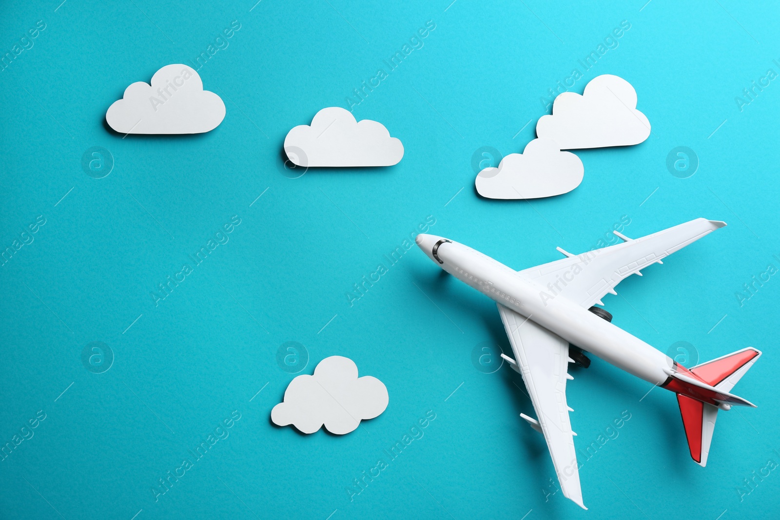 Photo of Toy airplane and clouds on light blue background, flat lay