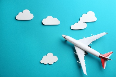 Photo of Toy airplane and clouds on light blue background, flat lay