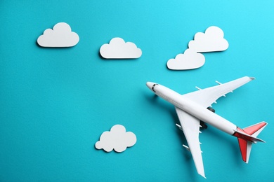 Toy airplane and clouds on light blue background, flat lay