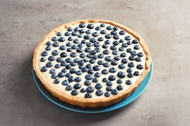 Photo of Plate with tasty blueberry cake on gray table