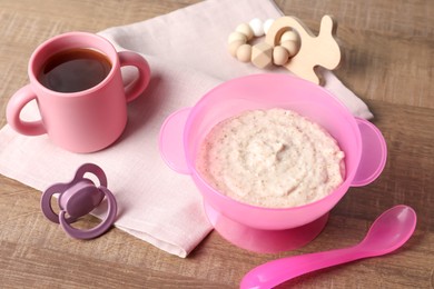 Baby food. Puree in bowl, drink, toy and soother on wooden table