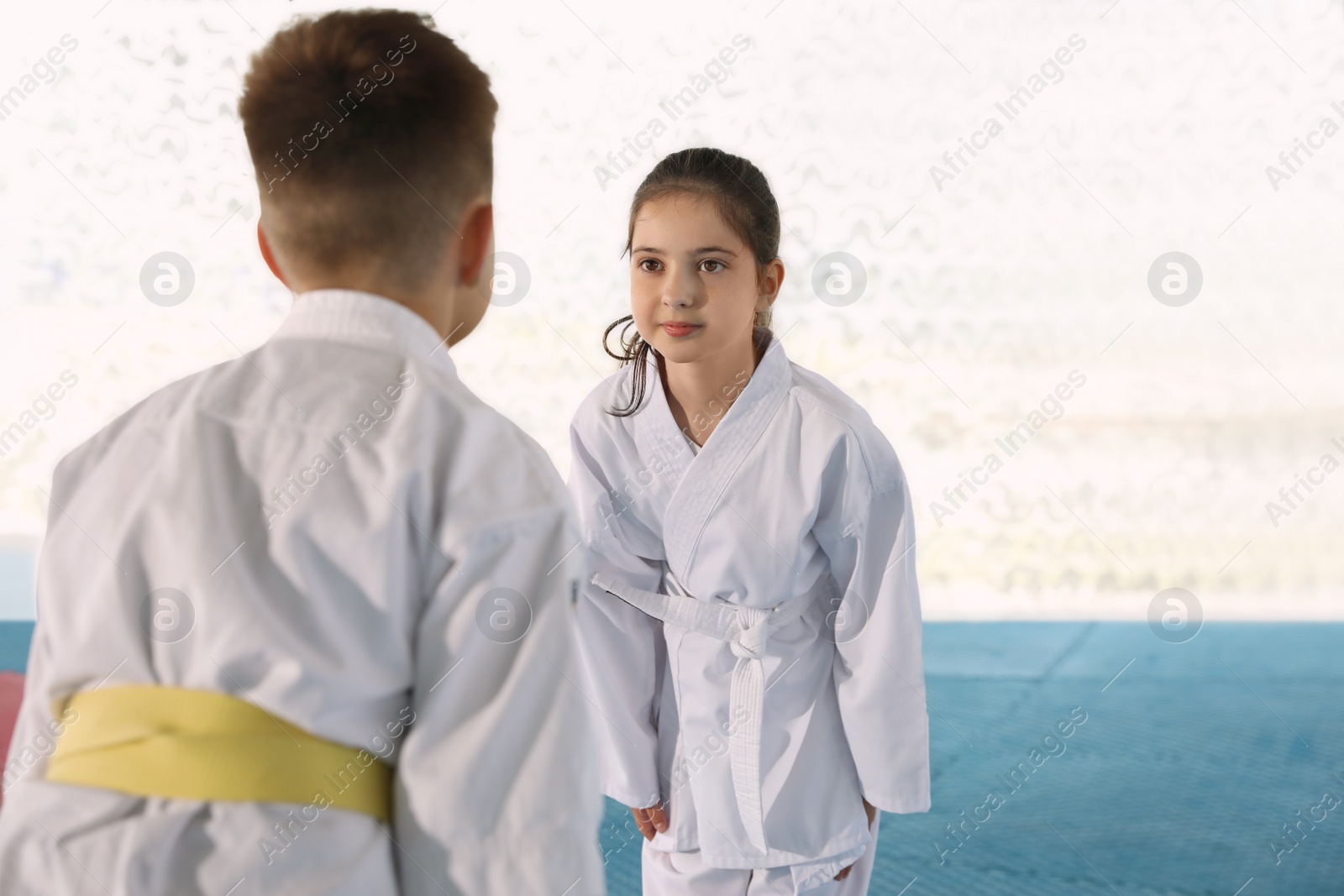 Photo of Children in kimono performing ritual bow before karate practice on tatami outdoors