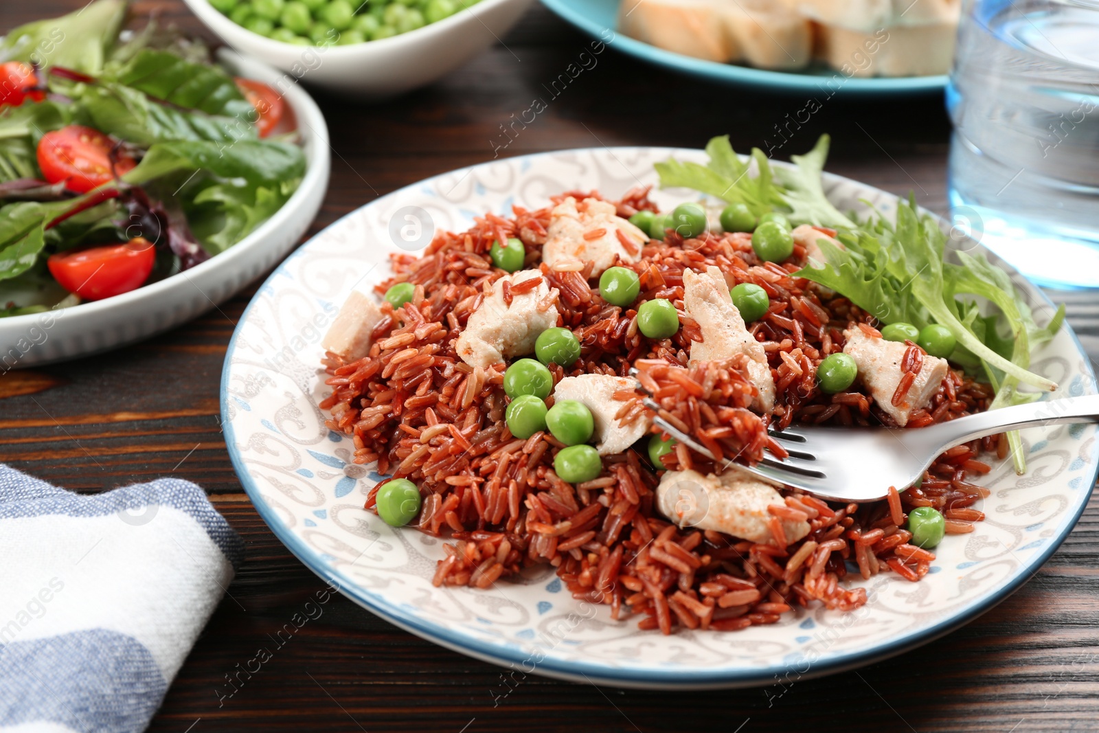 Photo of Tasty brown rice with meat and vegetables on wooden table