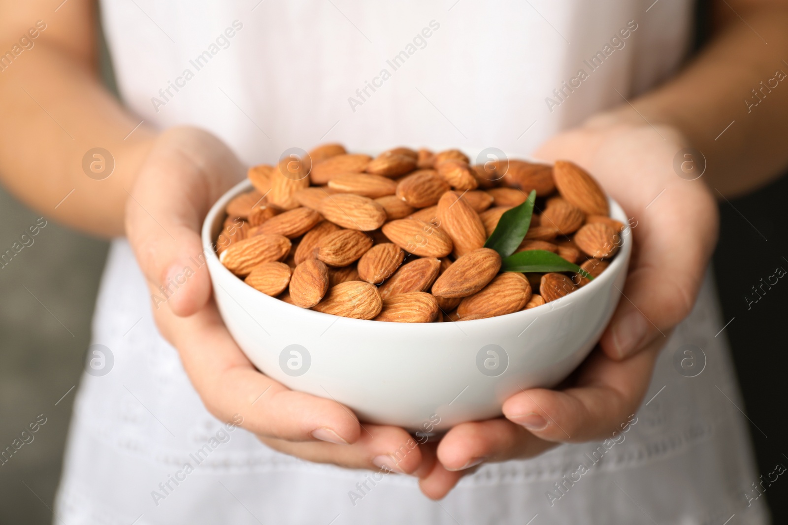 Photo of Woman holding bowl with organic almond nuts, closeup