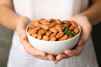 Woman holding bowl with organic almond nuts, closeup