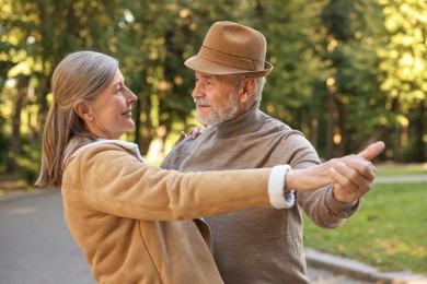 Photo of Affectionate senior couple dancing together in park. Romantic date