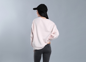 Photo of Young woman in sweater on grey background. Mock up for design