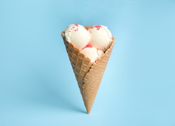 Photo of Delicious vanilla ice cream in wafer cone on blue background