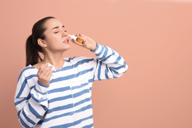 Photo of Woman using nasal spray on beige background, space for text