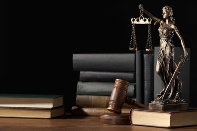 Photo of Symbol of fair treatment under law. Statue of Lady Justice near books and gavel on wooden table, space for text.