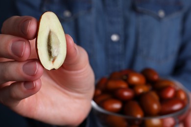 Photo of Woman holding half of fresh Ziziphus jujuba fruit, closeup