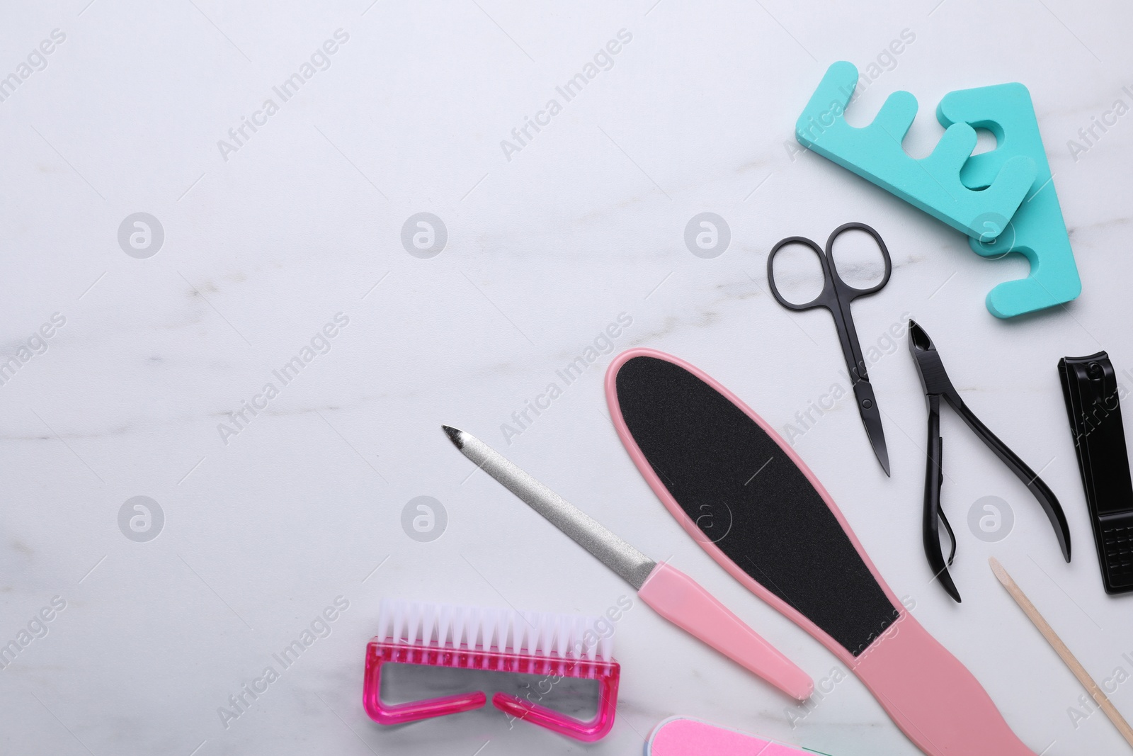 Photo of Set of pedicure tools on white marble table, flat lay. Space for text