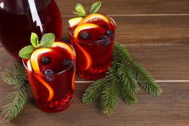 Photo of Aromatic Christmas Sangria drink and fir branches on wooden table