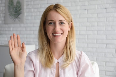 Woman talking to her coworkers through video conference indoors, view from webcam