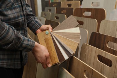 Photo of Man with samples of wooden flooring in shop, closeup