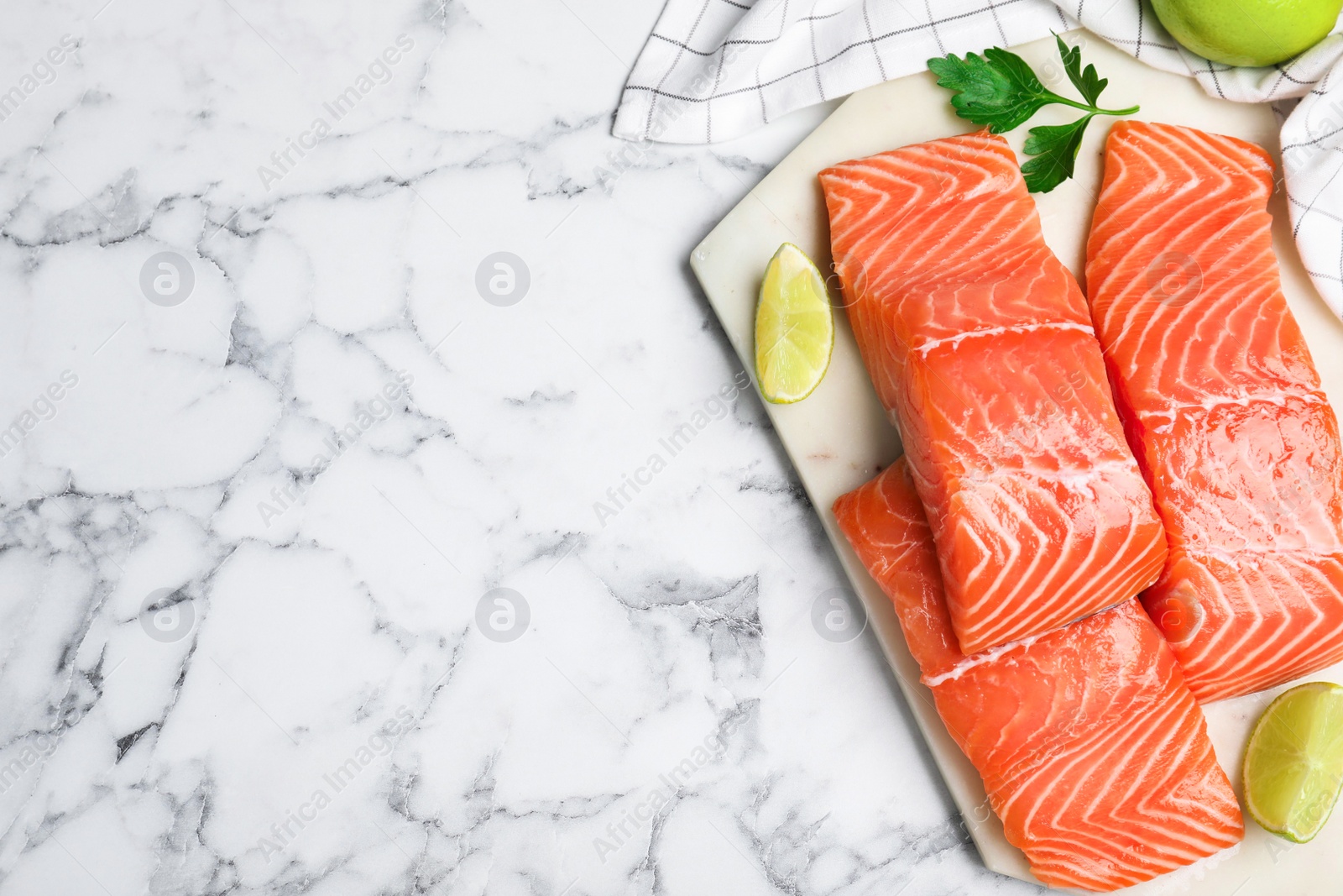 Photo of Top view of fresh raw salmon with lime and parsley on white marble table, space for text. Fish delicacy