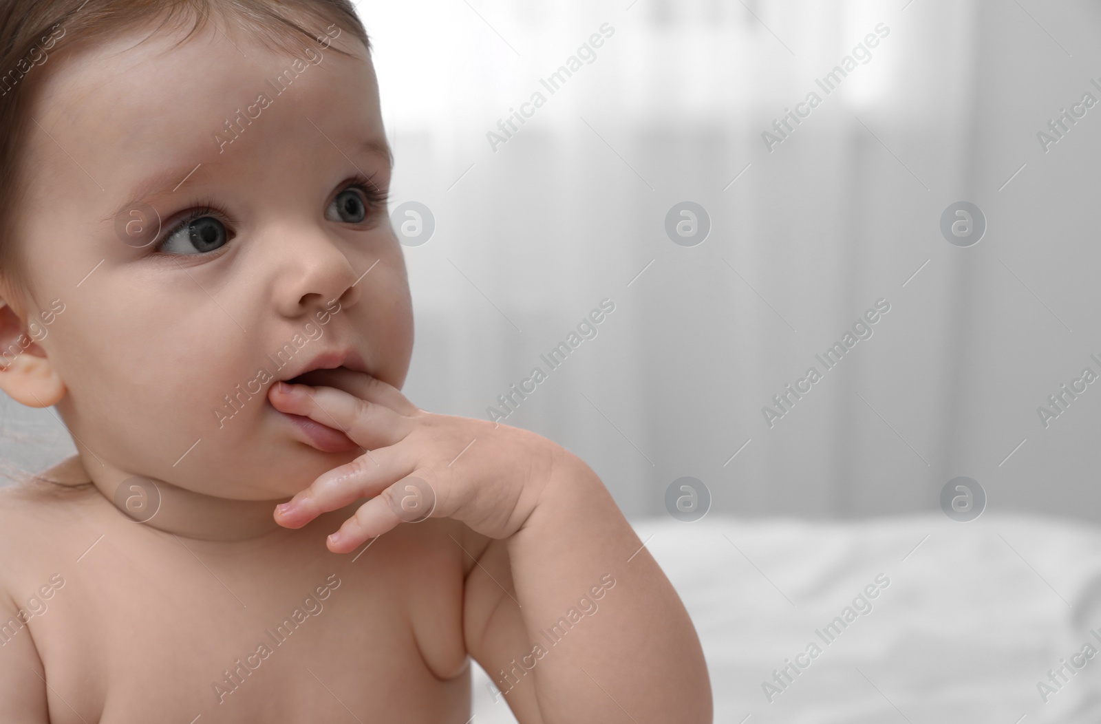 Photo of Cute little baby sitting on bed at home, closeup. Space for text