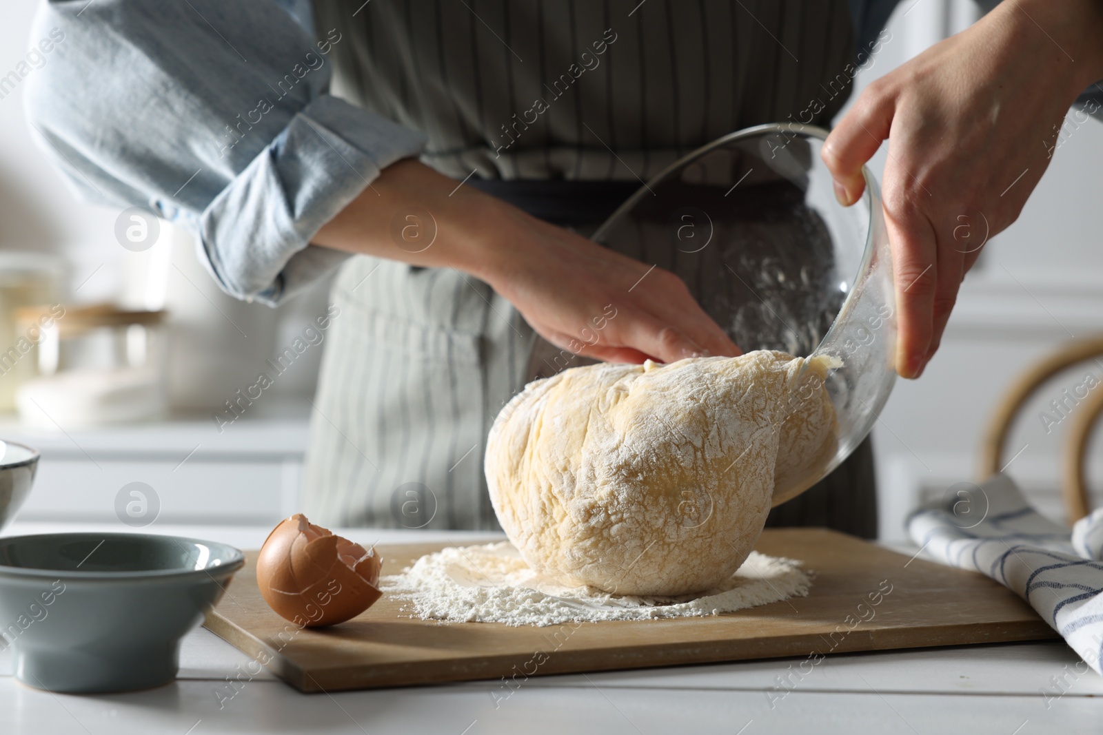 Photo of Woman kneading dough at white wooden table in kitchen, closeup