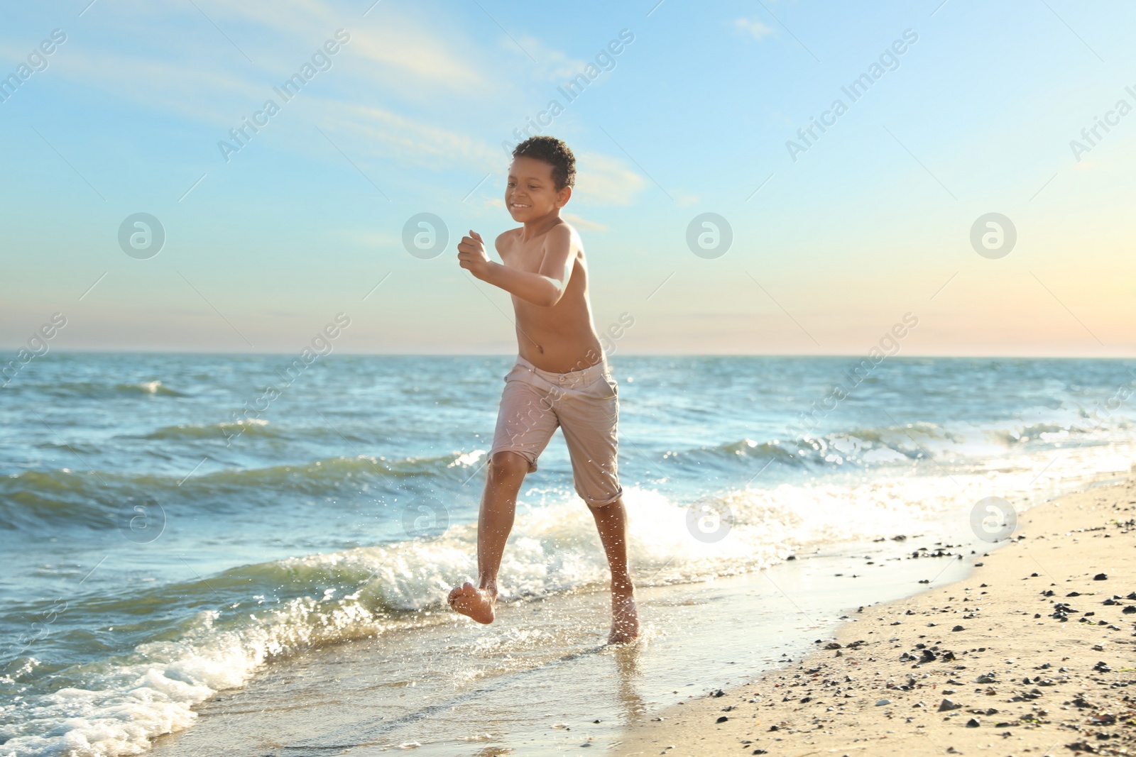 Photo of Cute African-American boy enjoying sunny day at beach. Summer camp