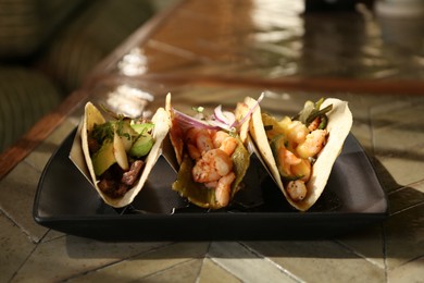 Delicious tacos with shrimps and vegetables on table