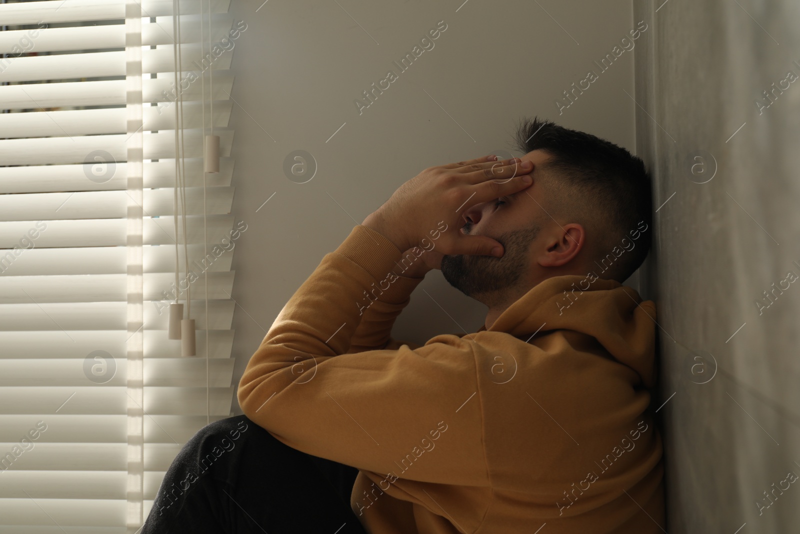 Photo of Sad man sitting near window. Space for text