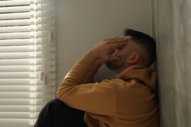 Photo of Sad man sitting near window. Space for text