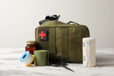 Photo of Military first aid kit, tourniquet, pills and elastic bandage on light grey table
