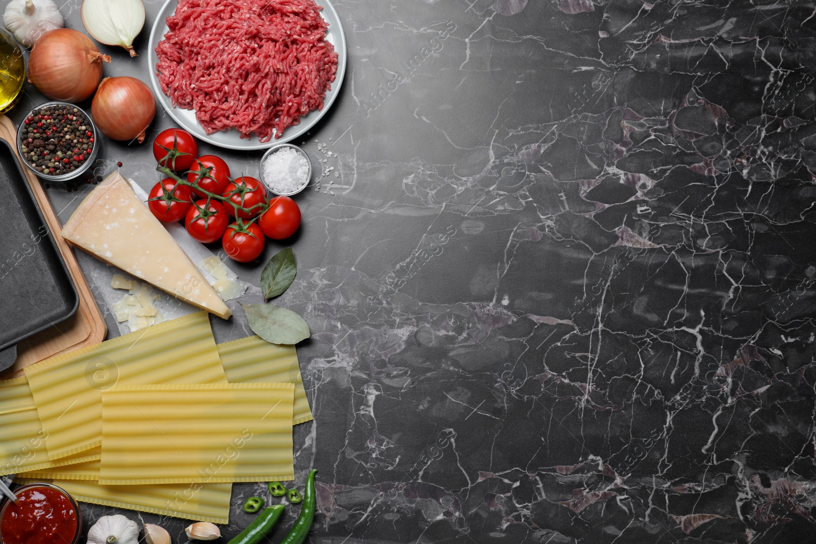 Photo of Fresh lasagna ingredients on black marble table, flat lay. Space for text