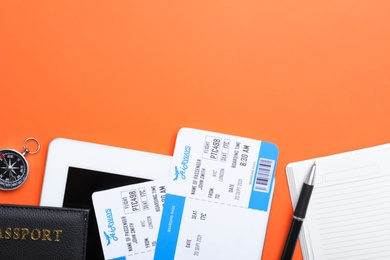 Flat lay composition with avia tickets on orange background, space for text. Travel agency concept