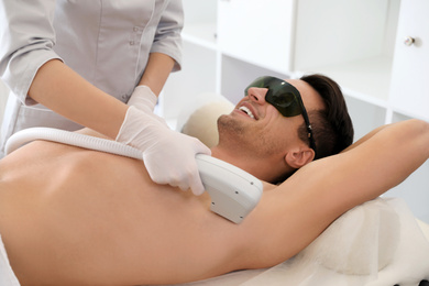 Photo of Young man undergoing laser epilation procedure in beauty salon