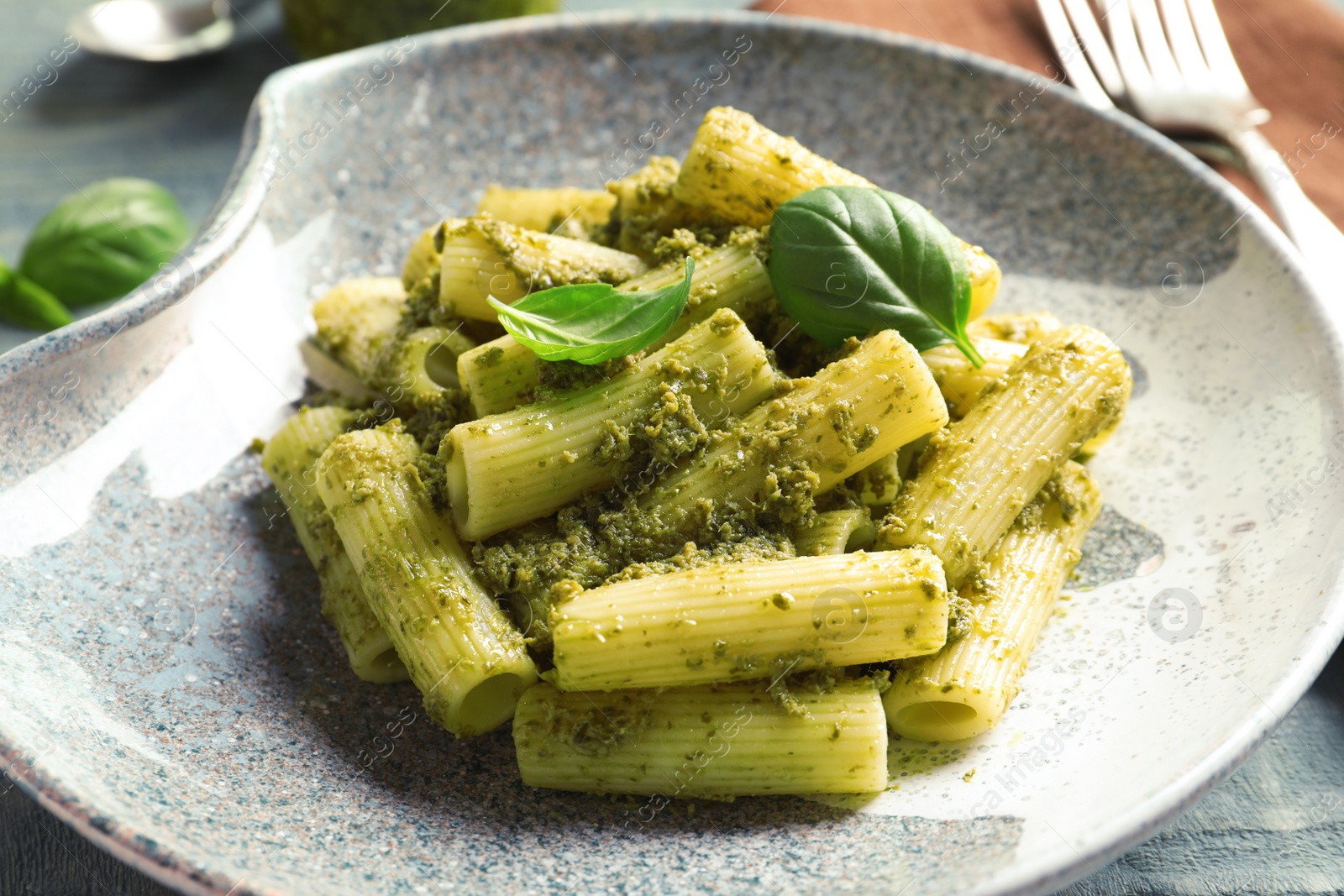 Photo of Plate with delicious basil pesto pasta on table