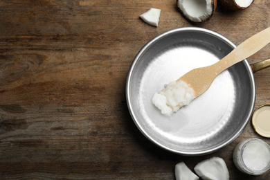 Photo of Flat lay composition with coconut oil and frying pan on wooden table, space for text. Healthy cooking