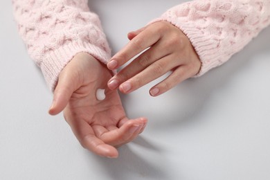 Woman applying cosmetic cream onto hand on light grey background, closeup