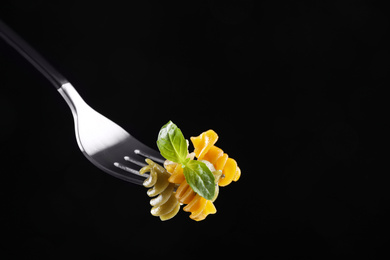 Photo of Fork with delicious spiraline pasta on black background