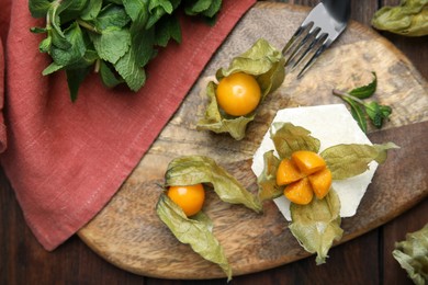 Photo of Delicious dessert decorated with physalis fruit on wooden table, top view