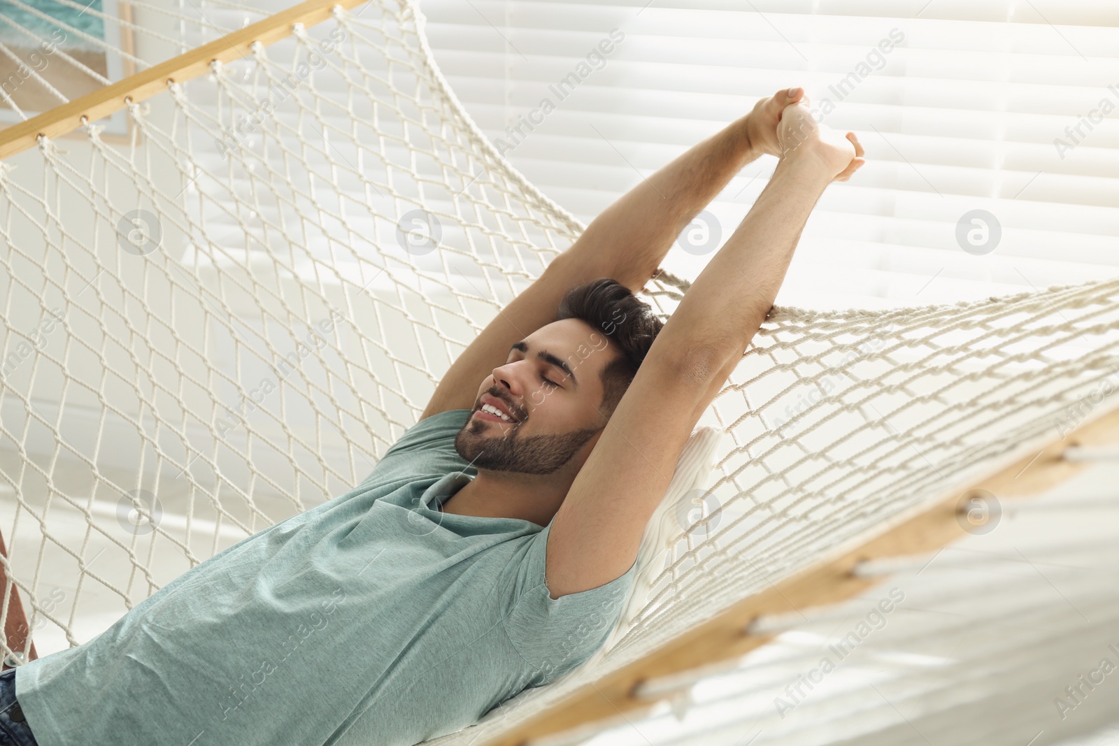 Photo of Young man relaxing in hammock at home