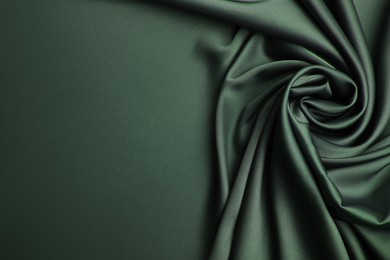 Image of Delicate dark green silk fabric as background, top view. Space for text