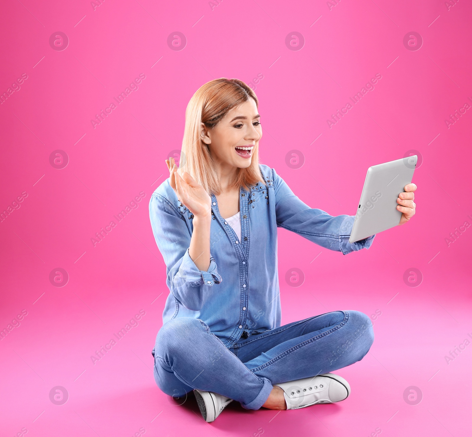 Photo of Woman using tablet for video chat on color background