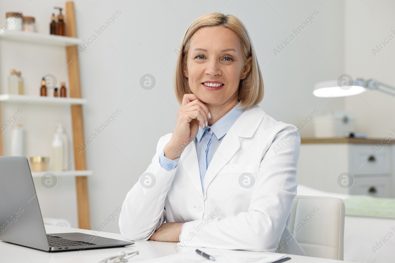 Photo of Portrait of happy dermatologist at white table in clinic