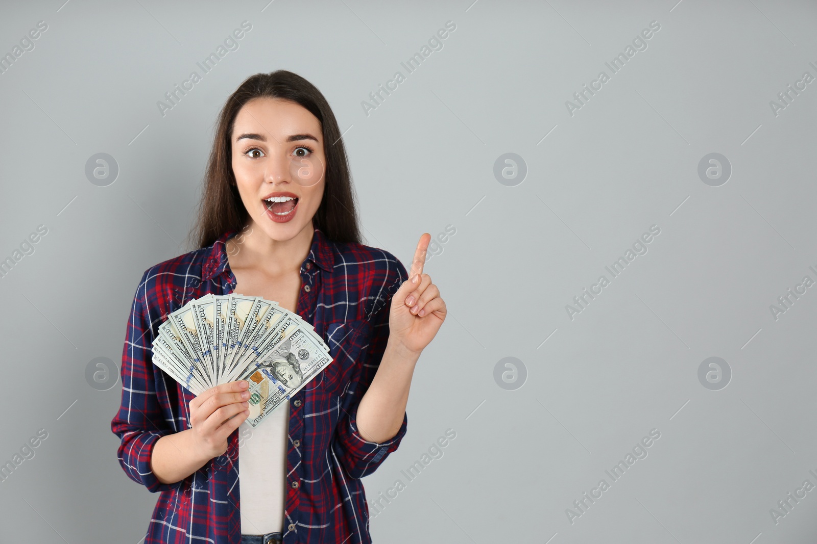 Photo of Emotional young woman with money on light grey background. Space for text