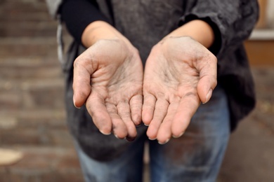 Poor homeless woman begging for help outdoors, closeup