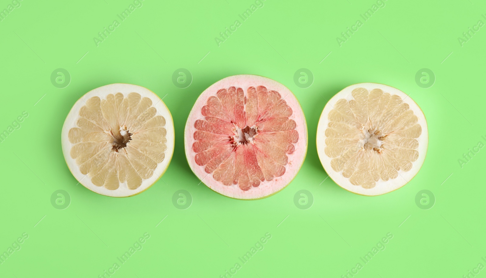 Photo of Fresh cut pomelo fruits on green background, flat lay