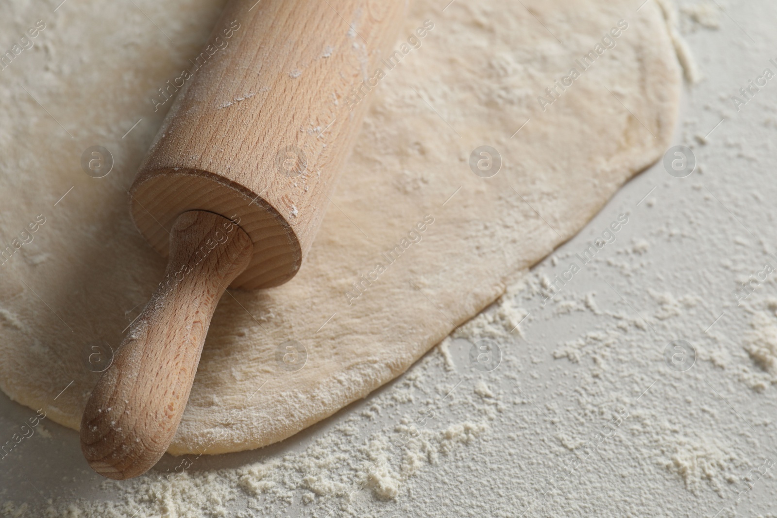 Photo of Raw dough and rolling pin on table, closeup