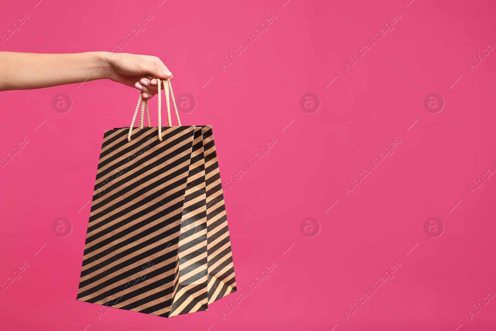 Photo of Young woman with paper bags on pink background, closeup. Space for text