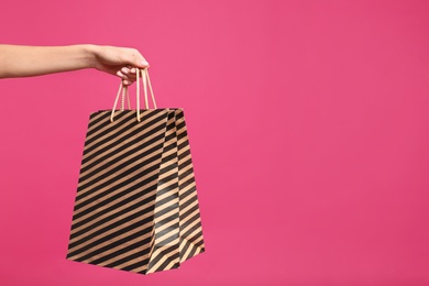 Photo of Young woman with paper bags on pink background, closeup. Space for text