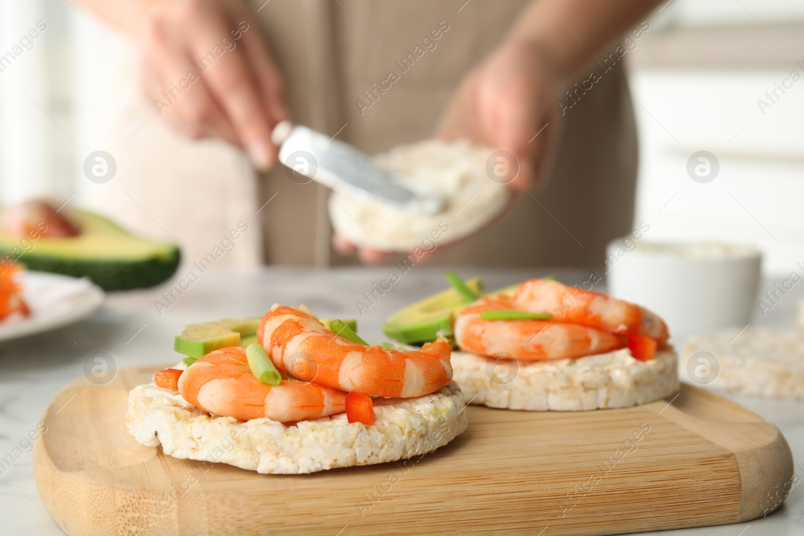 Photo of Puffed rice cake with shrimps and avocado on wooden board, closeup
