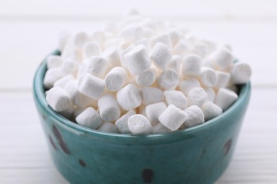 Photo of Bowl with delicious marshmallows on white table, closeup