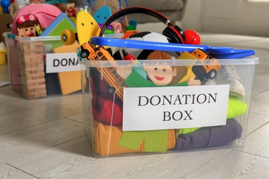 Photo of Donation boxes with different child toys on floor indoors