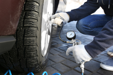 Photo of Mechanic checking tire air pressure at car service, closeup